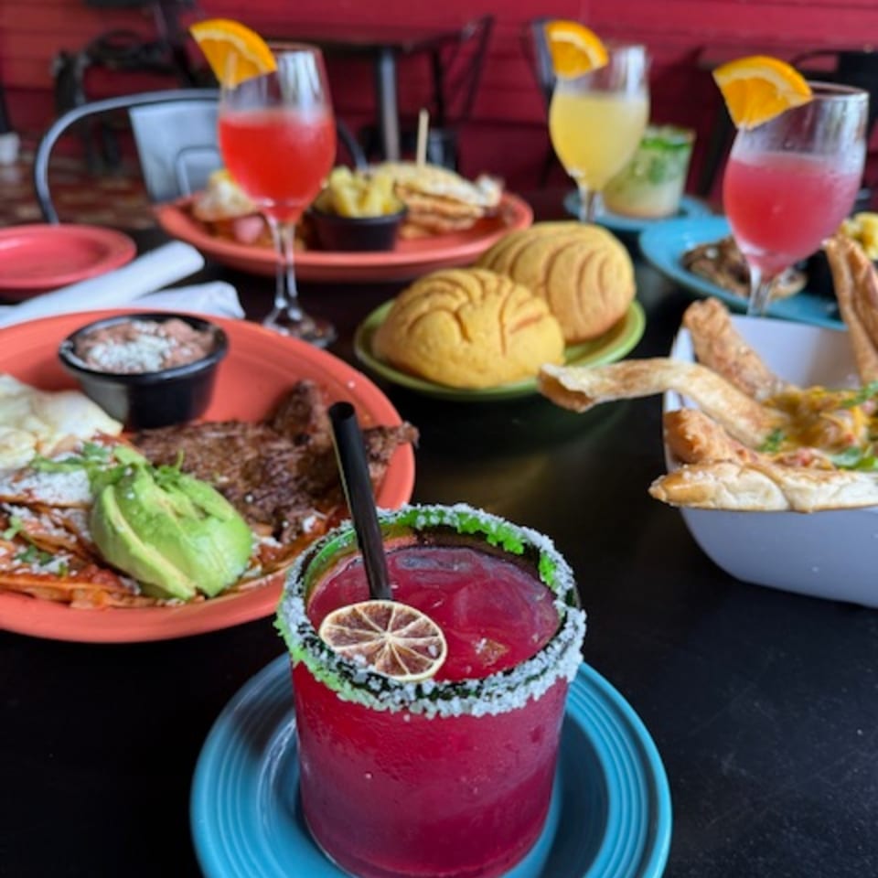 A vibrant Mexican feast with a red margarita, steak, avocado, beans, and sweet bread.